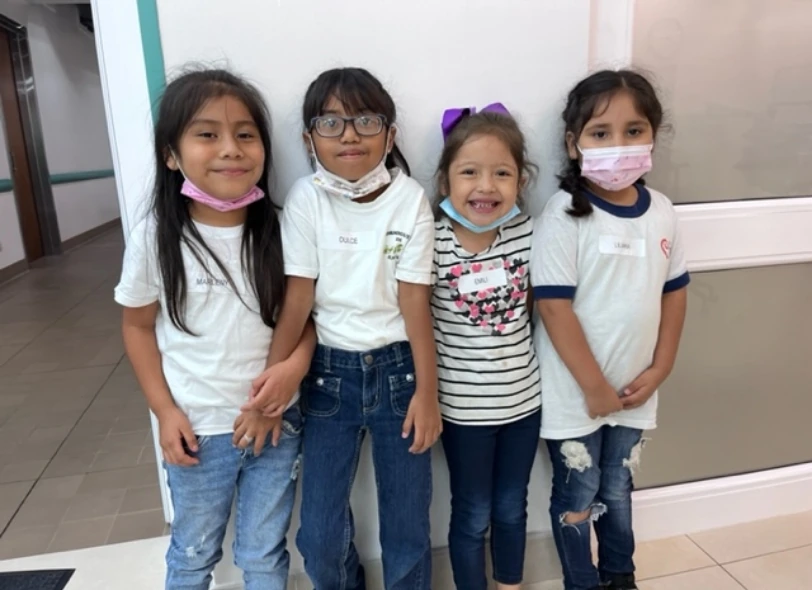 preventive dental care children A group of children wearing masks and standing in a hallway, likely at a school or