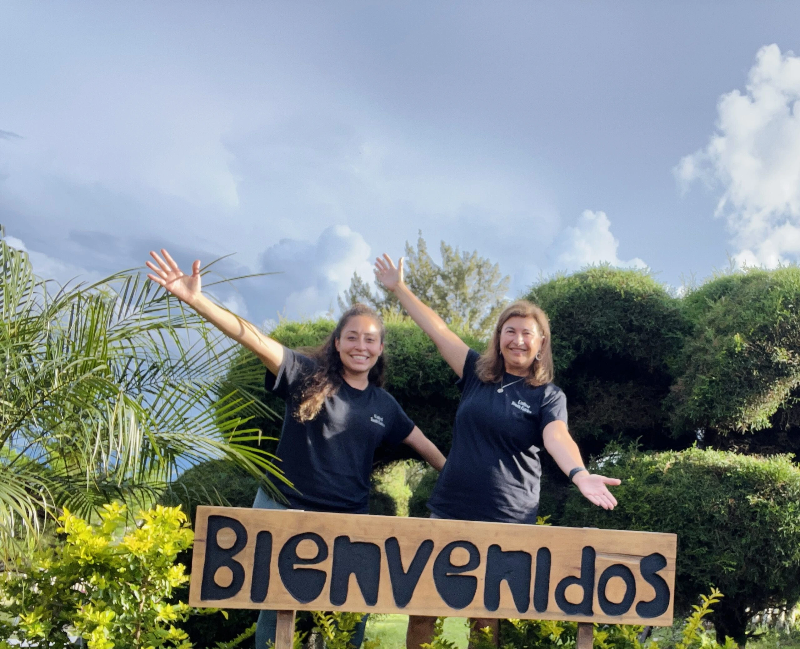 dental hygienist volunteers Guatemala Two women in matching black t-shirts stand behind a sign that says 'Bienvenidos' in